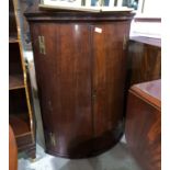 A Georgian mahogany bow front corner cupboard with 4 shelves and 3 drawers enclosed by 2 doors