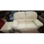 A cream leather 2 seater settee and matching pouffe