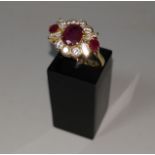 An 18 carat hallmarked gold ruby and diamond dress ring, set oval central ruby and 2 rubies either