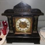 A mantel clock in ebonised wood architectural case, with brass dial and striking movement; an