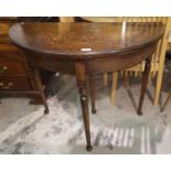 A 1930's fold-over card table with oak demi-lune top, on turned legs