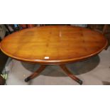 A reproduction oval yew wood pedestal coffee table
