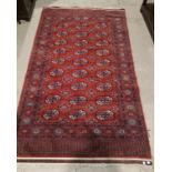 A 20th century hand knotted Bokhara rug with rust ground, 214 x 120 cm