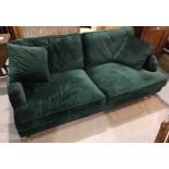 A Victorian style 3 seater settee in dark green velvet, on turned legs and castors