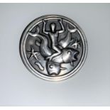 A Georg Jensen silver circular brooch depicting a merman with 2 large fish and starfish, model No