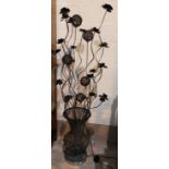 A brushed metal uplight; a metal sculpture flowering plant