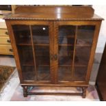 A 1930's oak display cabinet enclosed by 2 glazed doors