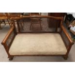 A 1930's walnut bergère caned settee on ball and claw feet