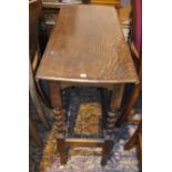 A 1930's oak drop leaf table with oval top, on barley twist legs