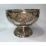 A late 19th/early 20th century silver plated punch bowl with embossed decoration, on raised foot