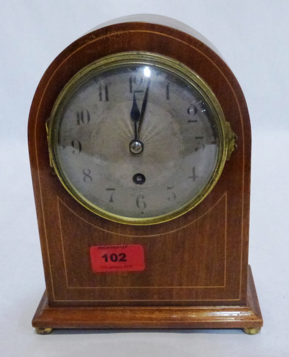 A mahogany and line inlaid mantle timepiece with silvered dial and French drum movement with