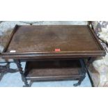 A 1920s oak barleytwist two tier tea trolley/card table with distressed green baize fold-over top