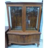A walnut display cabinet enclosed by a pair of glazed doors over serpentine cupboard base. 49' wide
