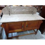 An early 20th century oak washstand enclosed by a pair of doors under a marble top and splashback.