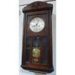 A 1930s oak wall clock, the twin barrel movement striking on a gong. 30' high