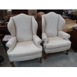 A pair of Queen Anne style upholstered wing armchairs on cabriole ball and claw legs