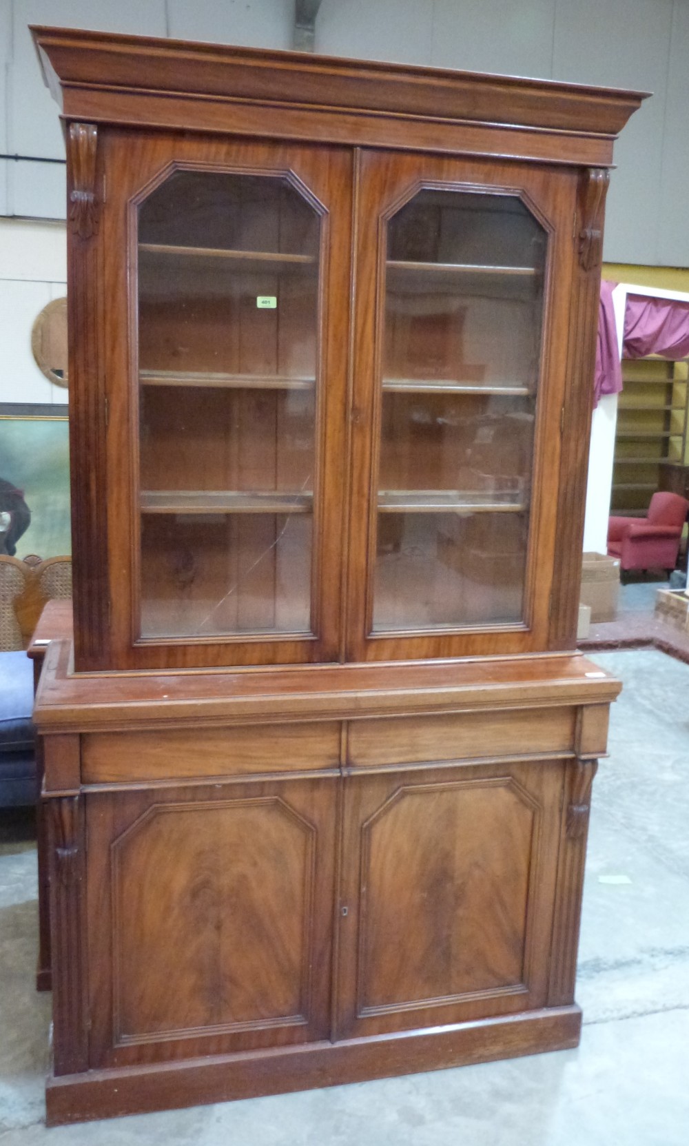 A Victorian mahogany bookcase enclosed by a pair of glazed doors over two frieze drawers and panel