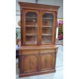 A Victorian mahogany bookcase enclosed by a pair of glazed doors over two frieze drawers and panel