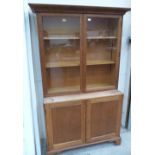 An early 20th century light oak bookcase, enclosed by a pair of glazed doors over a pair of panel