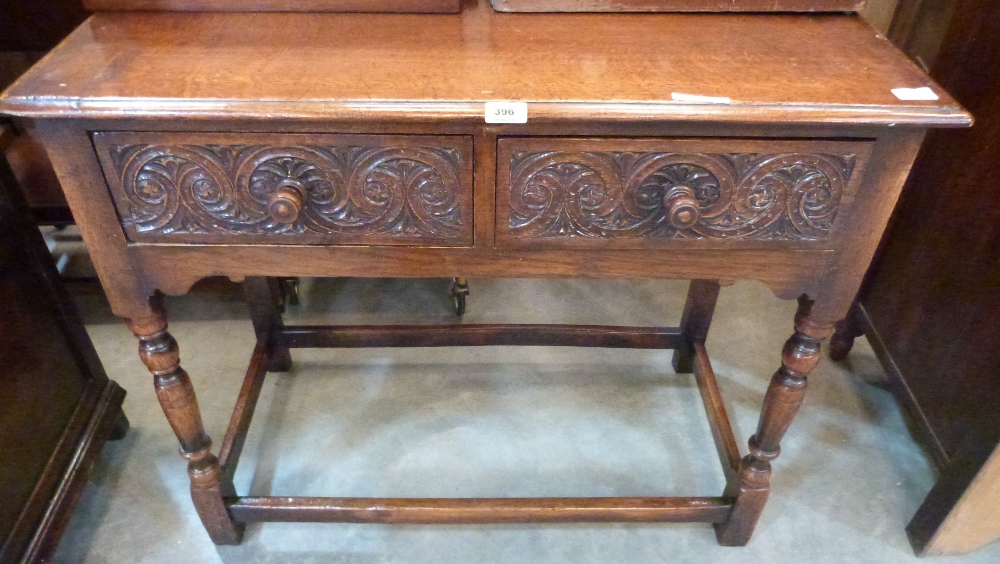 A joined oak side table in 17th century style with two carved frieze drawers on baluster turned legs