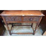 A joined oak side table in 17th century style with two carved frieze drawers on baluster turned legs