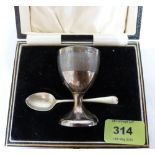 A George V cased silver christening eggcup with associated plated spoon. Birmingham 1930