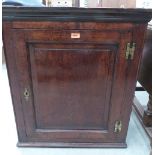 An 18th century joined oak wall cabinet, the panel door enclosing a pair of spice drawers and