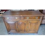 An oak sideboard with a pair of frieze drawers over three fielded panel doors. 54' wide