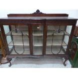 A 1920s mahogany china display cabinet enclosed by a pair of astragal glazed doors, on shell moulded