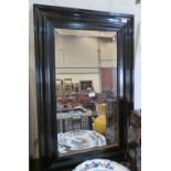 An ebonised wall mirror with bevelled plate