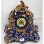 An early 20th century ceramic mantle timepiece, the rococo revival case gilded and blue glazed.