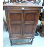 An oak cabinet enclosed by a pair of panel doors on barleytwist turned legs. 29' wide