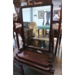 A Victorian mahogany dressing table mirror, the rectilinear swing plate on volute carved