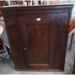 A George III elm and oak hanging corner cupboard enclosed by a panel door. 38' high