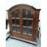 An eastern joined hardwood dome topped display cabinet enclosed by a pair of glazed doors over two