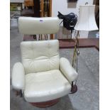 A reclining armchair and a brass lamp standard