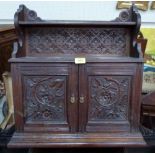 A carved oak wall cabinet enclosed by a pair of doors under a display shelf. 21' wide