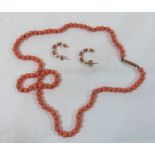 A necklace of coral beads with a pair of coral and seed pearl earrings