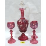 A German ruby glass hock decanter and three goblets with foliate enamel decoration