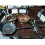 A long handled copper pan, two copper pans and a pair of hames