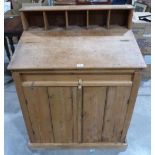 A pine bureau cupboard, the sloping fall over a pair of doors on plinth support