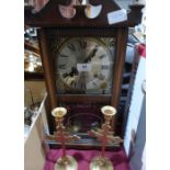 A wall clock and a pair of brass candlesticks