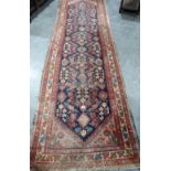 An eastern red ground carpet runner. 132' x 40'. Faded and loss to edge