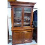 A Victorian mahogany bookcase, the upper part enclosed by a pair of glazed doors, over a frieze