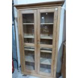 A pine bookcase, the shelved interior enclosed by a pair of glazed doors. 42' wide
