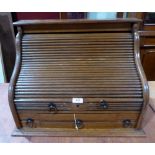 An oak roll-top writing desk, enclosed by a tambour slide over three drawers. 16½' h x 22' w