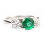 AN EMERALD AND DIAMOND THREE STONE RING