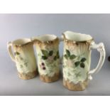 A GRADUATED SET OF THREE FLORAL DECORATED JUGS AND TREEN GOBLETS