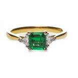 AN EMERALD AND DIAMOND THREE STONE RING