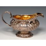 A GEORGE IV GADROONED SILVER CREAM JUG chased with flowers, 9cm h, maker's mark rubbed, London 1824,